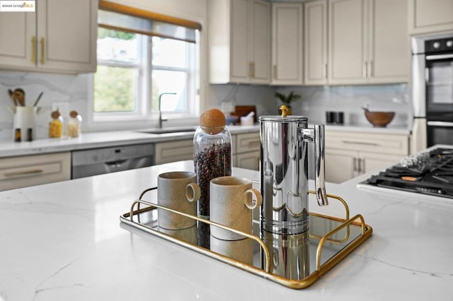 kitchen with stainless steel appliances, sink, backsplash, and light stone countertops