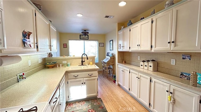 kitchen featuring visible vents, light countertops, a sink, and white cabinetry