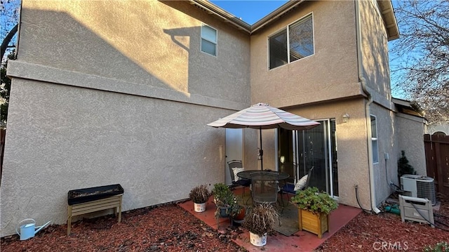 back of house with central AC unit, fence, and stucco siding