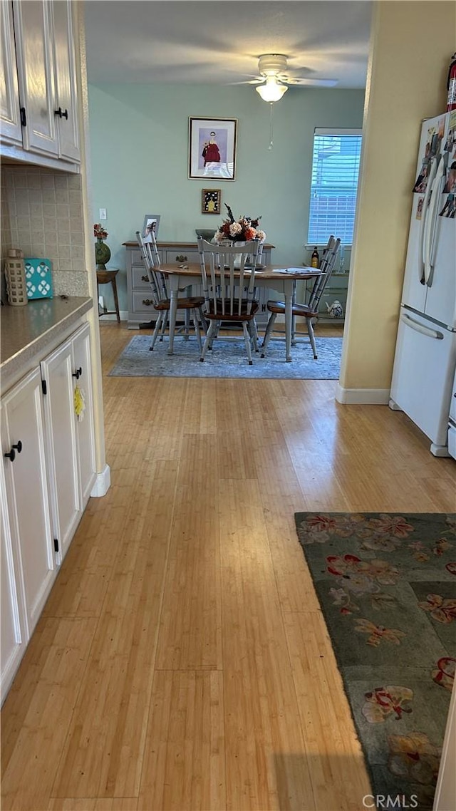 dining area with light wood-style floors, ceiling fan, and baseboards