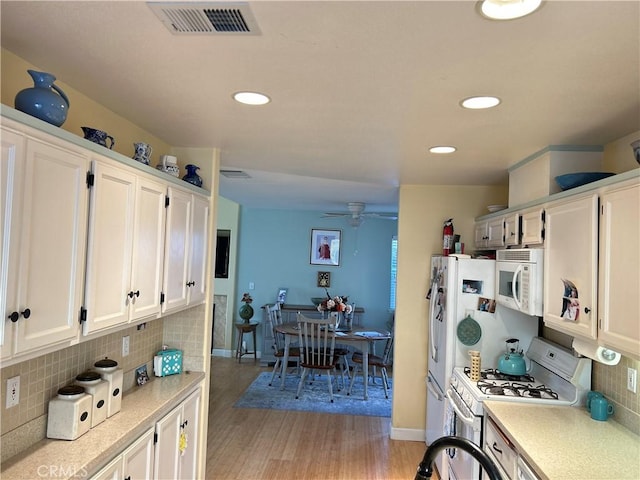 kitchen featuring white cabinets, light countertops, white appliances, and visible vents