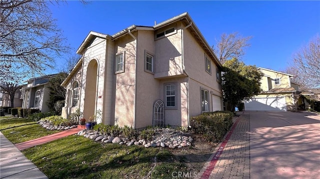 view of side of home with a garage, concrete driveway, and stucco siding