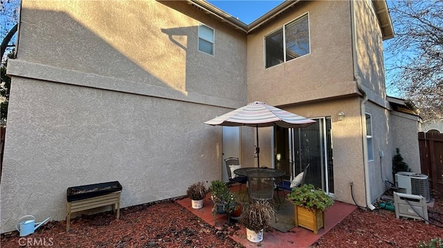 back of house featuring cooling unit, fence, and stucco siding