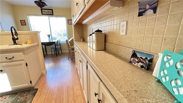 kitchen with light wood-style floors, tasteful backsplash, white cabinetry, and light countertops