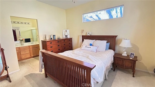 bedroom featuring ensuite bathroom, baseboards, and light colored carpet