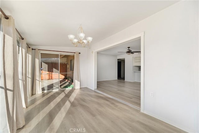 unfurnished dining area featuring ceiling fan with notable chandelier and hardwood / wood-style flooring