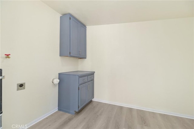 laundry area with electric dryer hookup, light wood-type flooring, and cabinets