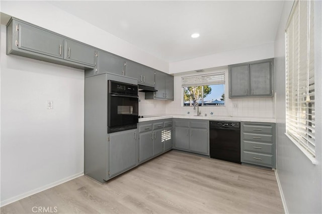 kitchen with black appliances, gray cabinetry, decorative backsplash, sink, and light hardwood / wood-style flooring