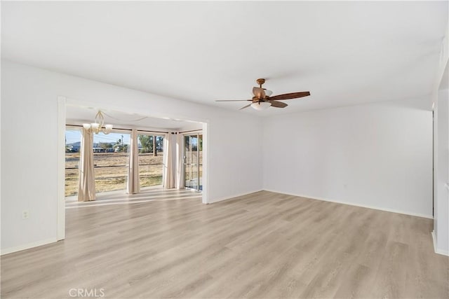 unfurnished room with light wood-type flooring and ceiling fan with notable chandelier