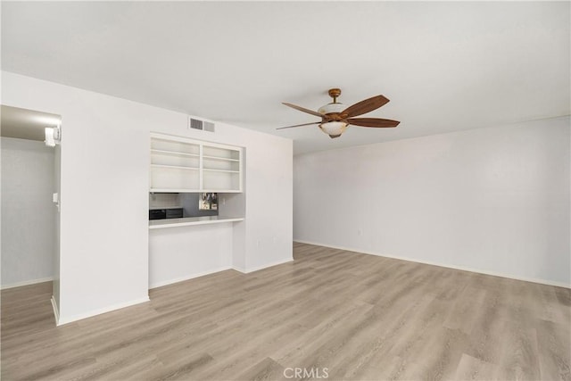 unfurnished living room with ceiling fan, light wood-type flooring, and built in shelves