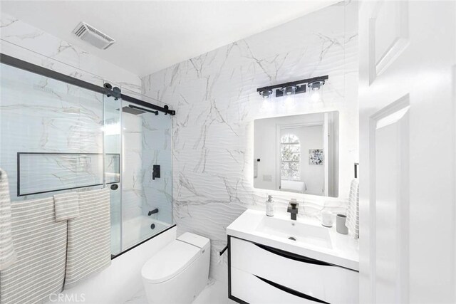 full bath with toilet, bath / shower combo with glass door, vanity, visible vents, and tile walls