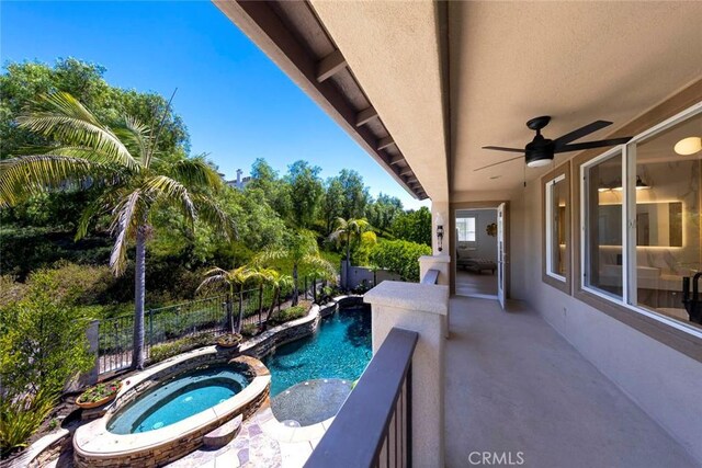 view of swimming pool with a ceiling fan, a pool with connected hot tub, and fence