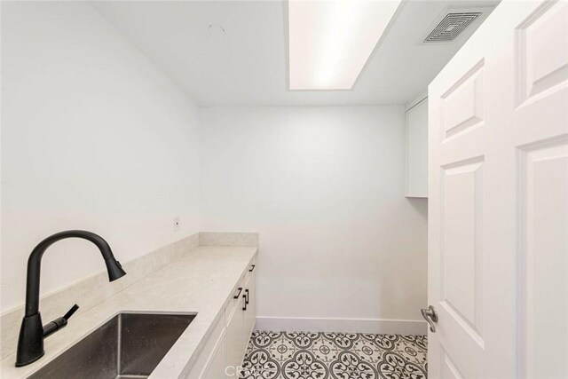 laundry area with a sink, visible vents, and baseboards