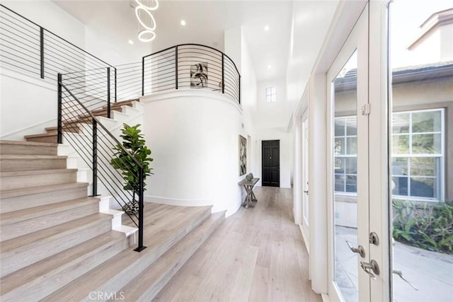 foyer entrance with baseboards, stairway, a high ceiling, light wood-style floors, and recessed lighting