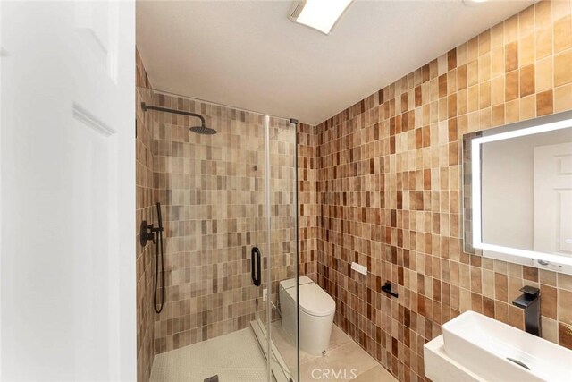 bathroom with tile patterned flooring, a sink, tile walls, and toilet