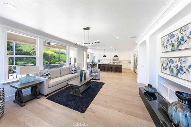 living area featuring baseboards, light wood finished floors, recessed lighting, and crown molding