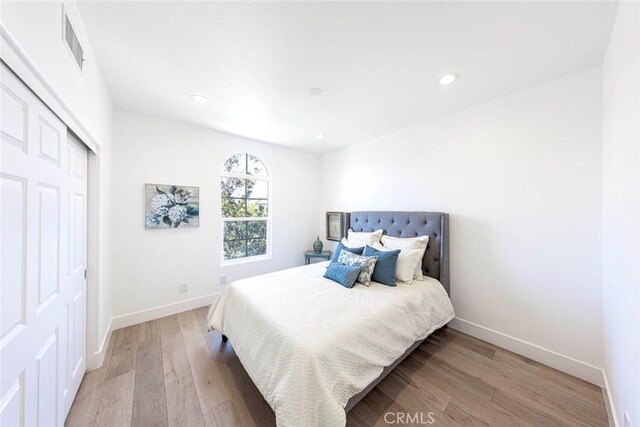 bedroom featuring recessed lighting, wood finished floors, visible vents, baseboards, and a closet