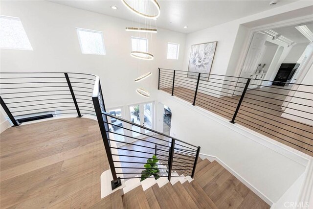 stairs with a high ceiling, wood finished floors, a wealth of natural light, and recessed lighting