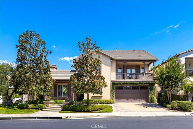 view of front of home featuring a garage, concrete driveway, a balcony, and stucco siding