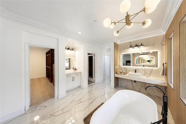 full bathroom with marble finish floor, crown molding, a freestanding bath, an inviting chandelier, and vanity