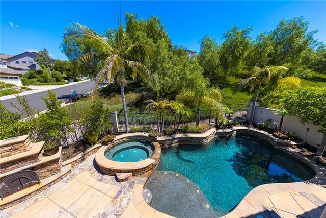 view of pool featuring a patio, a fenced backyard, and a pool with connected hot tub