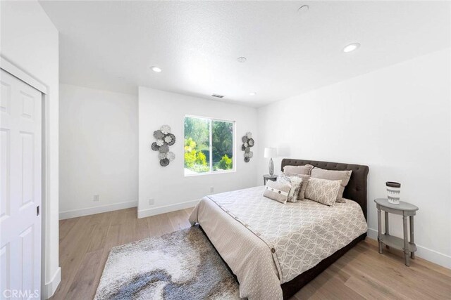 bedroom with recessed lighting, light wood-type flooring, and baseboards