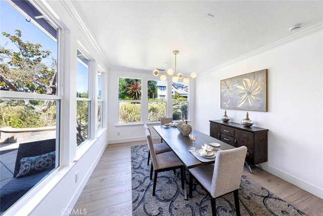 dining space featuring light wood-style flooring, baseboards, and crown molding