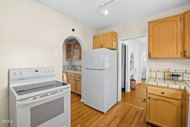 kitchen with white appliances, tile countertops, and light hardwood / wood-style floors