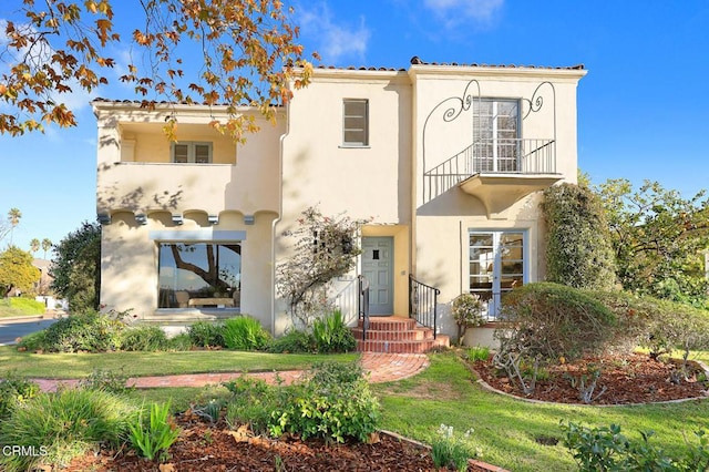 mediterranean / spanish home featuring a balcony and a front lawn