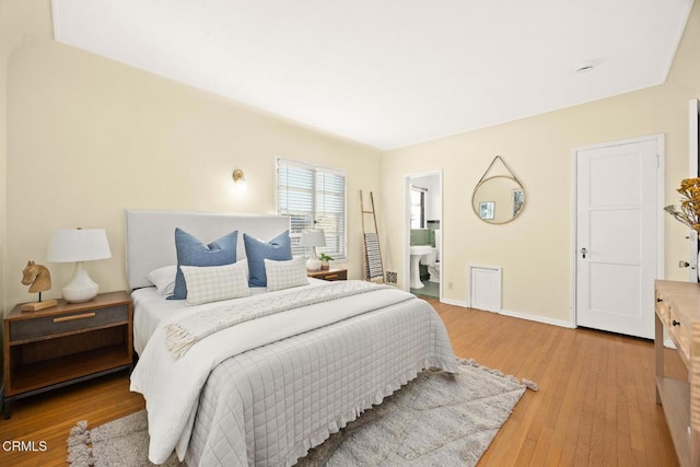 bedroom with ensuite bathroom and hardwood / wood-style flooring