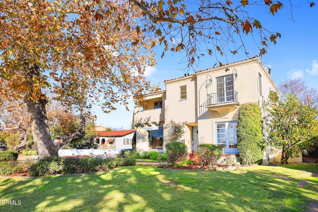 view of front of house featuring a balcony and a front yard