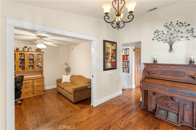 living area featuring wood-type flooring and ceiling fan with notable chandelier