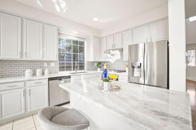 kitchen with light stone countertops, appliances with stainless steel finishes, white cabinetry, and sink