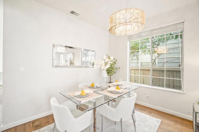 dining area featuring hardwood / wood-style flooring and an inviting chandelier