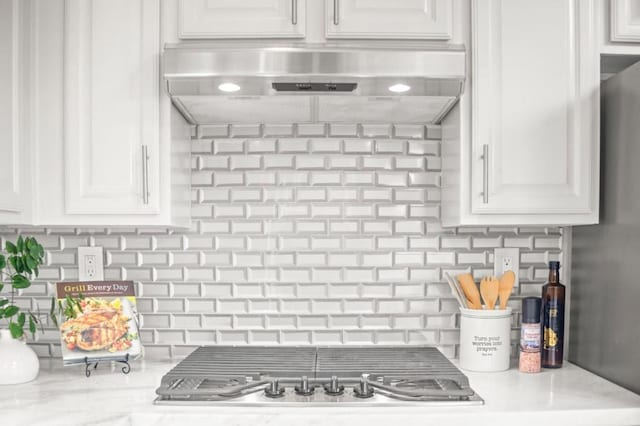 kitchen with white cabinets, light stone counters, and decorative backsplash