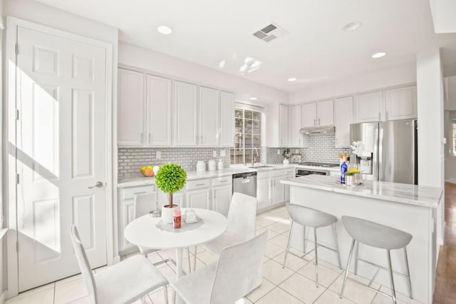 kitchen with a center island, a breakfast bar, white cabinets, appliances with stainless steel finishes, and sink