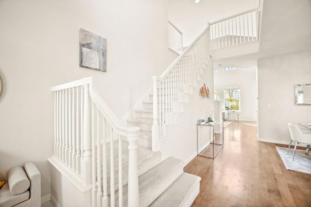 stairs featuring a high ceiling and hardwood / wood-style flooring