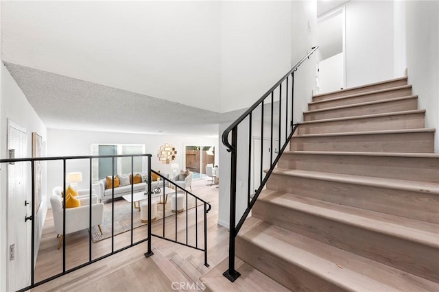 stairs with a textured ceiling and hardwood / wood-style floors