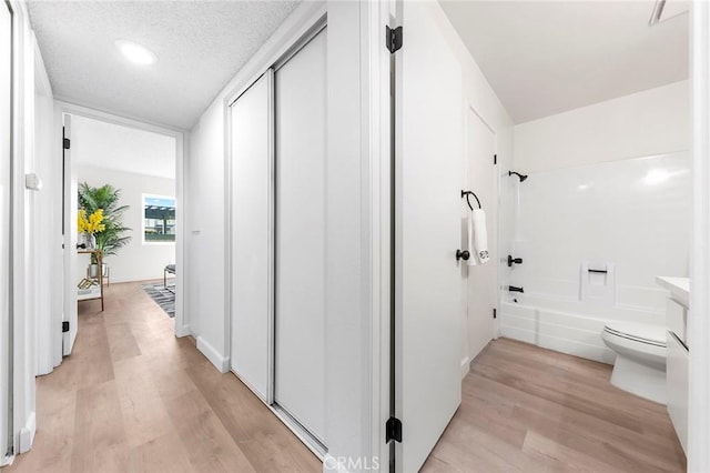 corridor featuring light hardwood / wood-style floors and a textured ceiling