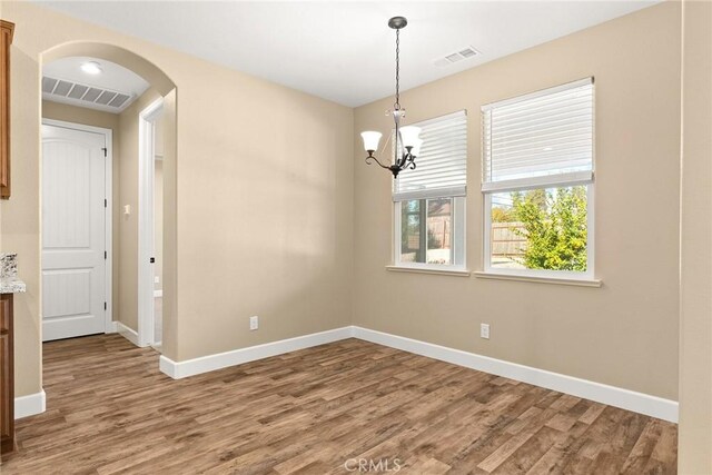 unfurnished dining area featuring hardwood / wood-style flooring and a chandelier