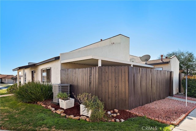 view of side of home featuring cooling unit and a lawn