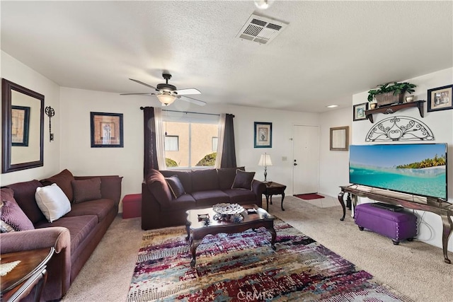 living room with ceiling fan, a textured ceiling, and light carpet