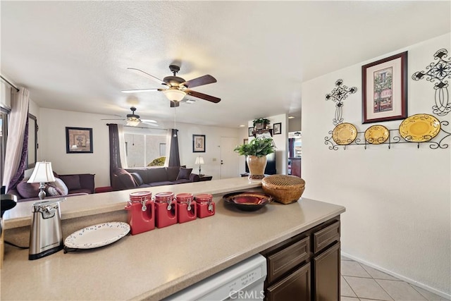 kitchen with a textured ceiling, light tile patterned flooring, a healthy amount of sunlight, and dishwasher