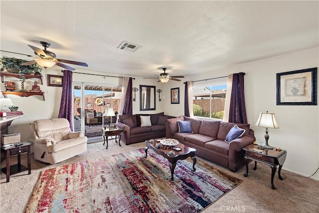 living room featuring light carpet, ceiling fan, and a textured ceiling