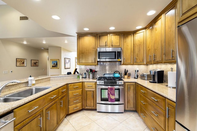 kitchen featuring light stone counters, kitchen peninsula, light tile patterned floors, appliances with stainless steel finishes, and sink