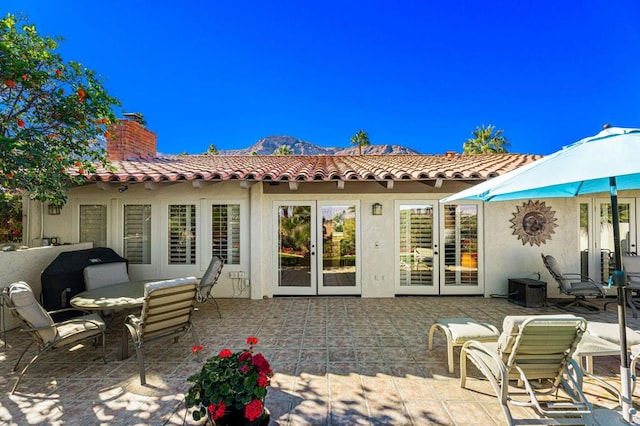 back of property with french doors, a mountain view, and a patio area