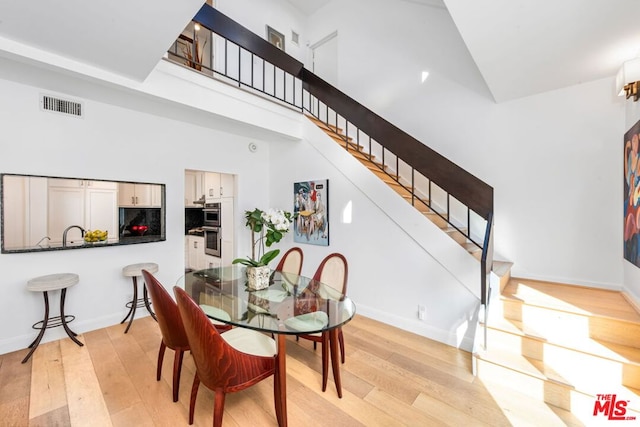 dining area with light hardwood / wood-style floors and a high ceiling