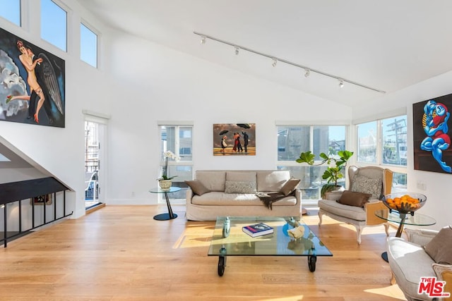 living room featuring high vaulted ceiling, rail lighting, and light wood-type flooring