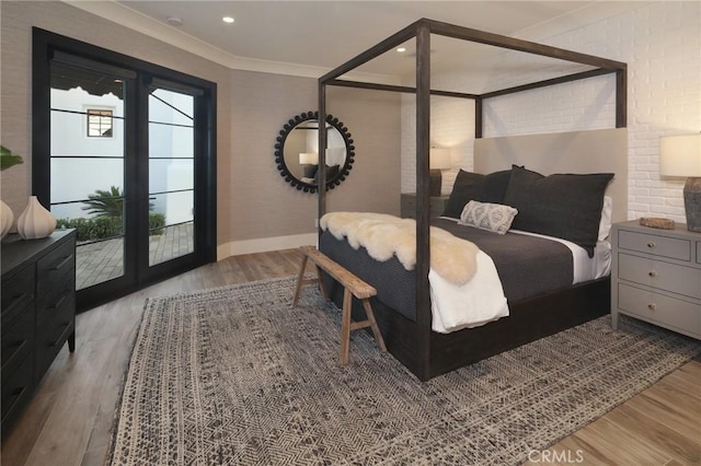 bedroom featuring ornamental molding, brick wall, access to exterior, and hardwood / wood-style floors