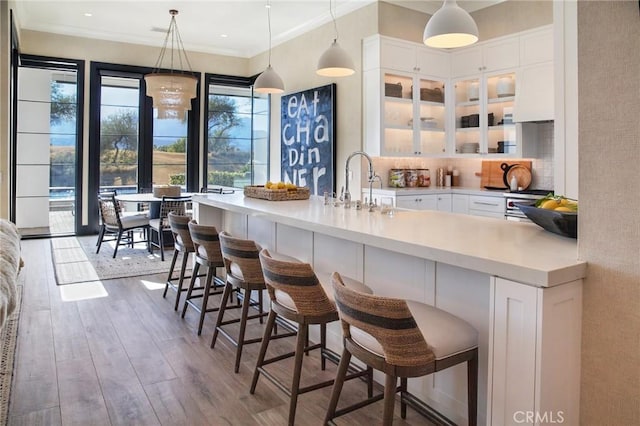 bar with hardwood / wood-style flooring, ornamental molding, white cabinets, and decorative light fixtures